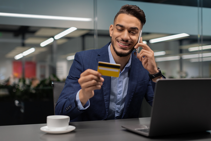 Man smiling on the phone and paying bills using an Aspire Credit Card